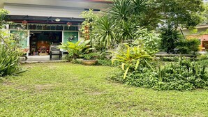 A small, single-story building with a red roof, surrounded by lush greenery and various plants. - Rider Resort and coffee (Chawang)