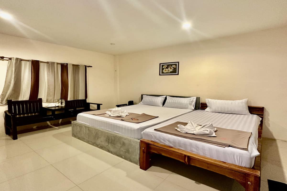 Habitación de hotel con dos camas, un banco y una mesita.