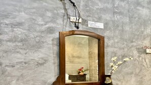 A wooden vanity with a mirror, a small table, and a vase with flowers. - Rider Resort and coffee (Chawang)