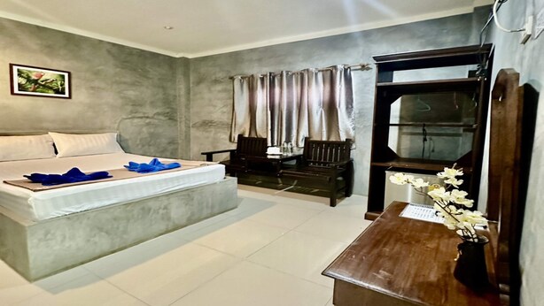 A bedroom with a bed, a desk, a chair, a TV, and a window with curtains. - Rider Resort and coffee (Chawang)