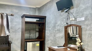 A room with a wooden desk, a mirror, a television mounted on the wall, and a wardrobe with a small refrigerator inside. - Rider Resort and coffee (Chawang)