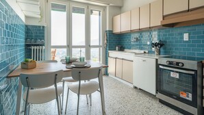 Une cuisine moderne avec un coin repas, dotée d’une grande fenêtre, d’un crédence en carreaux bleus et d’un four encastré.
