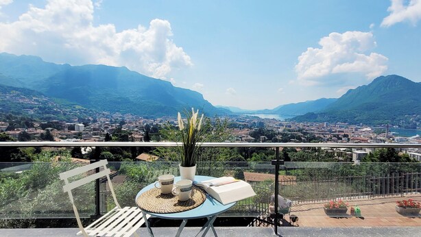 Un balcon avec une table, des chaises et une vue sur la ville et les montagnes.