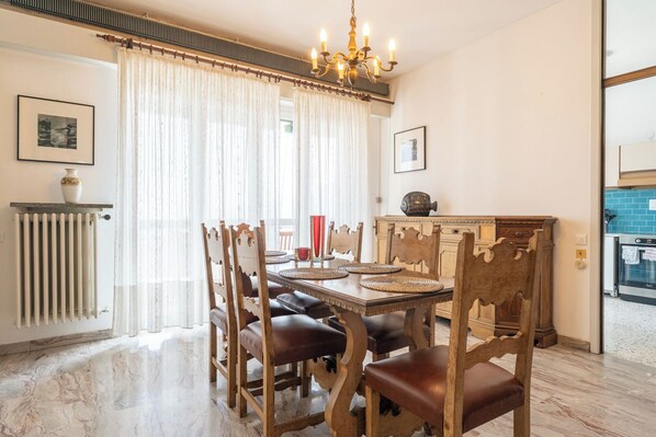 Un comedor con una mesa de madera, sillas, una lámpara de araña y un radiador.