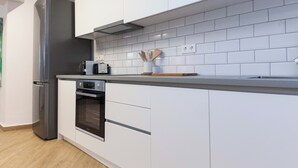A modern kitchen with white cabinets, a stainless steel refrigerator, an oven, and a microwave. - Kipseli New Modern Cosy Apts Apt No 5 (Athens)