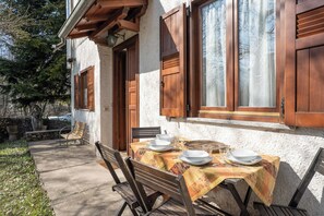 Un espace de restauration en plein air avec une table dressée pour deux personnes, des chaises en bois et un banc.