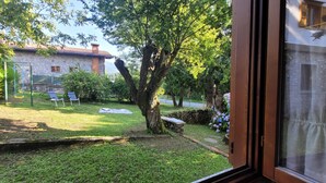 A view of a stone building with a garden in front, including a swing set and a bench.
