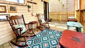 Un patio acogedor con muebles de madera, un tapete estampado y plantas colgantes.