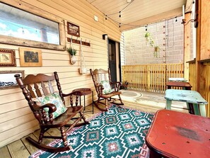 Una zona patio accogliente con mobili in legno, un tappeto decorato e piante pensili.