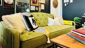 Un sofá verde con varios cojines y una mesita baja con libros.