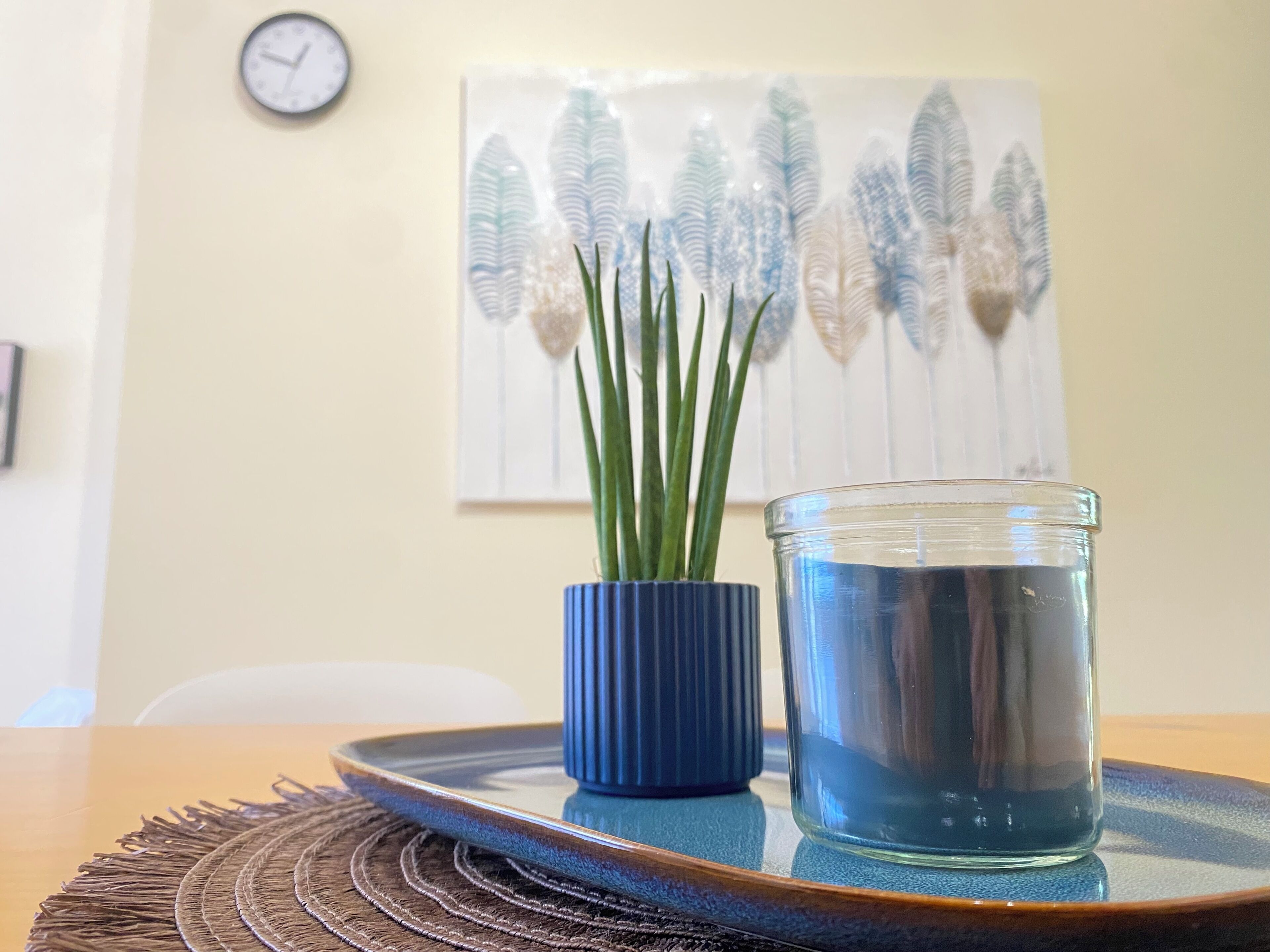 Une table avec un vase bleu, un verre d’eau et un set de table en fibres tressées.