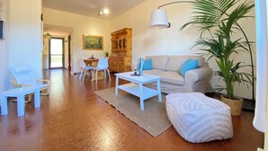 A living room with a sofa, coffee table, and chairs. There is a dining area in the background with a table and chairs. A large plant is in the corner. - SunsetView - Lake Como swimming pool and garden (Lierna)