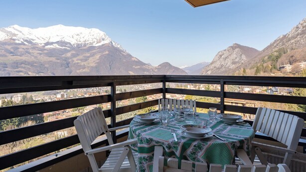 Een balkon met een eettafel, met uitzicht op een bergachtig landschap.