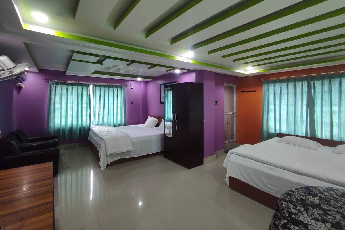 A hotel room with two beds, a wardrobe, a desk, and a mirror.