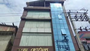 A hotel with a modern glass facade and a sign in a local script. - Raj Hotel (Baksa)