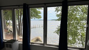 A room with a large window overlooking a lake, curtains, and a radiator. - Winnipesaukee luxury waterfront 3-BDR home w/dock, views, AC, laundry, beach (Moultonborough)