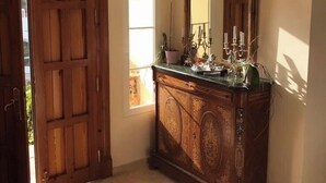 A room with a wooden door, a mirror with a decorative frame, a cabinet with a marble top, and a small window. - Boutique Villa Marbella (Marbella)