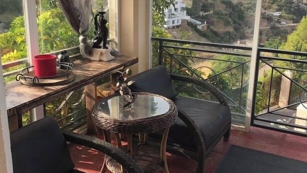 A balcony with wicker furniture, a red cup, and a view of a coastal town. - Boutique Villa Marbella (Marbella)