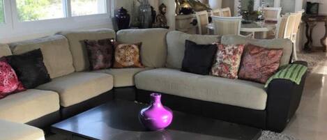 A living room with a sectional sofa, a coffee table, and a chandelier.