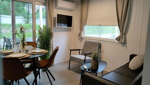 Een moderne kamer met een eethoek, een bank en een aan de muur bevestigde televisie.