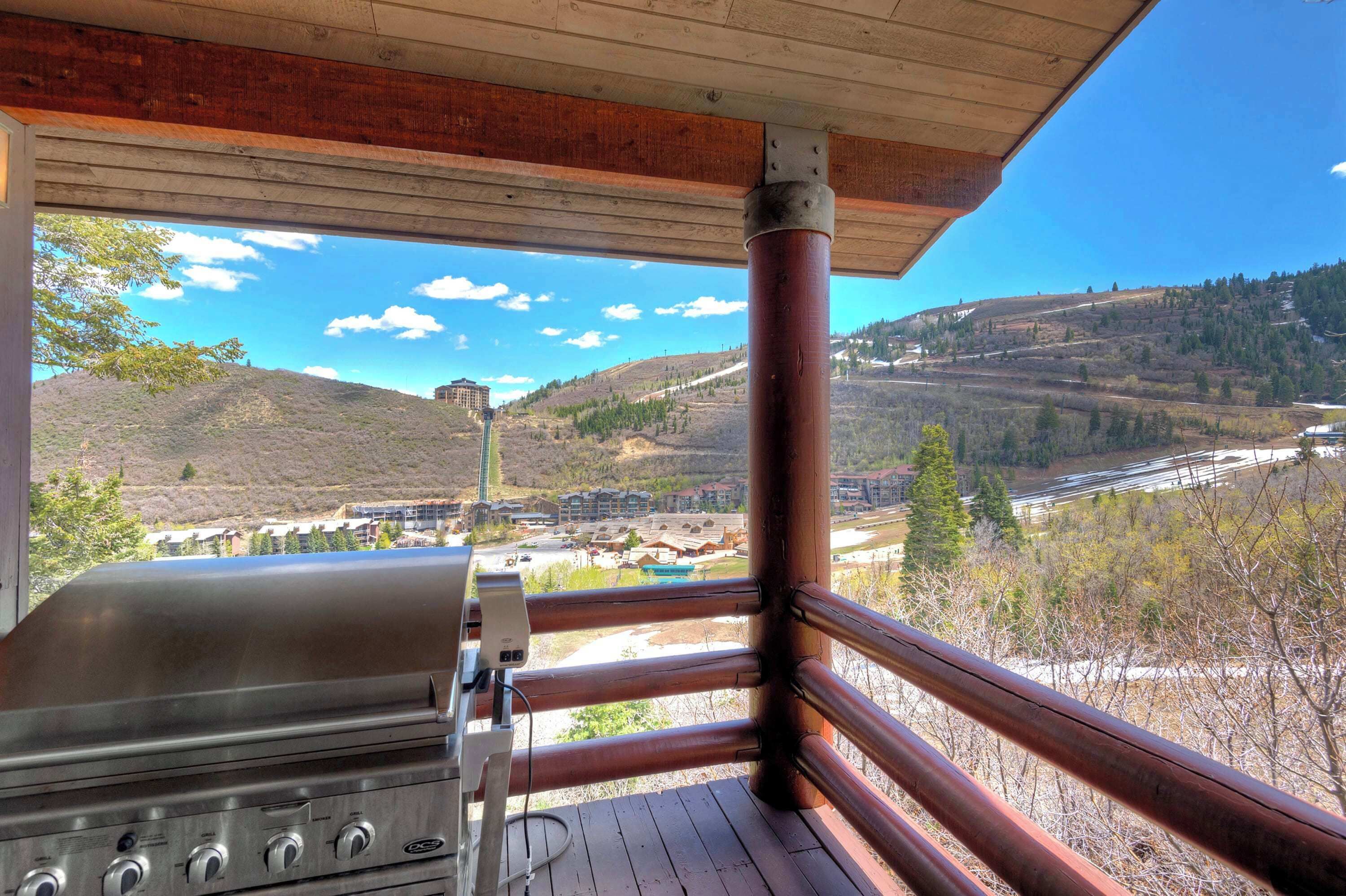 Eine Holzterrasse mit Grill, mit Blick auf ein Tal mit Gebäuden und einem Fluss.