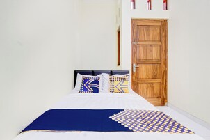 Cama com roupa de cama branca e um cobertor com padrão azul e amarelo.