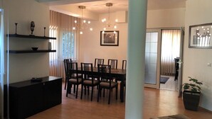 A dining area with a table and chairs, a black cabinet, and a potted plant. - LILU HOUSE ,5-bedroom villa in peaceful Câmpina with WiFi (Câmpina)