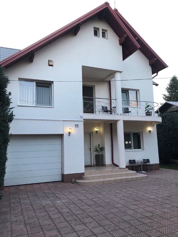 A two-story house with a balcony, a garage, and a paved driveway. - LILU HOUSE ,5-bedroom villa in peaceful Câmpina with WiFi (Câmpina)