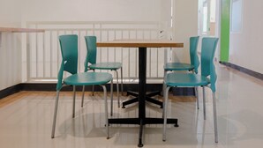 Una habitación con una mesa de madera y cuatro sillas color turquesa.