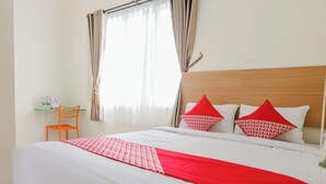 Una cama bien hecha con ropa de cama roja y blanca, un cabecero de madera y dos almohadas rojas con diseños blancos.