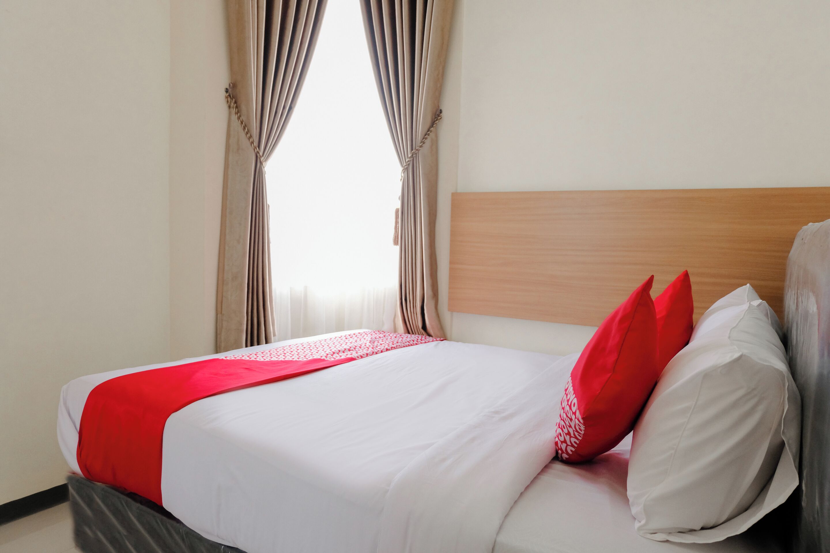 A neatly made bed with a white and red bedspread, two pillows, and a wooden headboard.