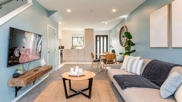 A modern living room with a flat-screen TV, a wooden coffee table, and a sofa.