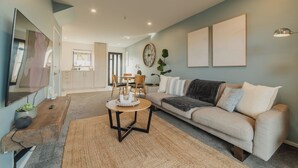 Una sala de estar con sofá, mesa de centro, televisor y un comedor con sillas y una mesa.