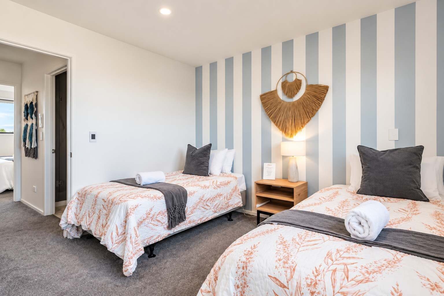 Une chambre d’hôtel avec deux lits, une lampe fixée au mur et une porte donnant sur un balcon.