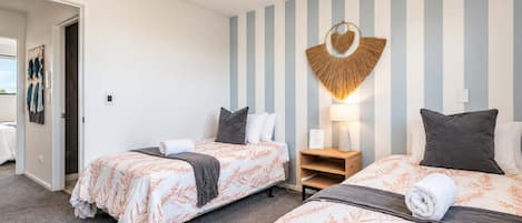Habitación de hotel con dos camas, una lámpara de pared y una puerta que da a un balcón.