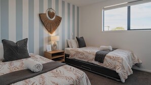 Habitación de hotel con dos camas, paredes a rayas, un ventanal grande y un adorno en la pared.