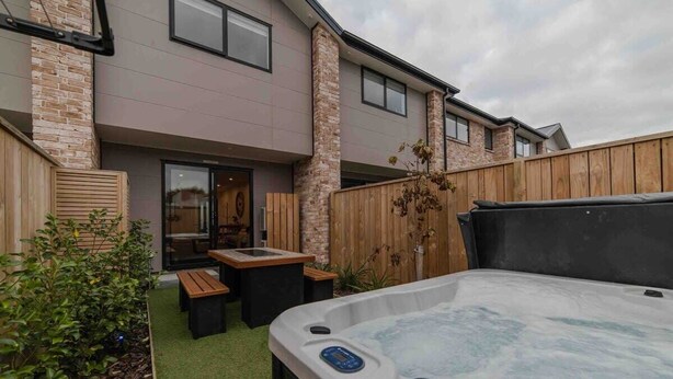 Un edificio moderno con jacuzzi, terraza de madera y zona de estar al aire libre.