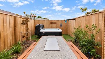 A backyard with a hot tub, a wooden fence, and a sign that reads 'Oana.'
