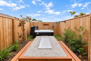 Un jardin avec un jacuzzi, une clôture en bois et une pancarte sur laquelle on peut lire « Oana ».