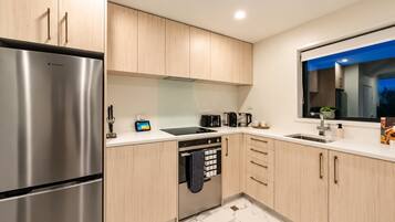 A modern kitchen with stainless steel appliances, wooden cabinets, and a marble floor.