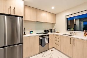 Una cocina moderna con electrodomésticos de acero inoxidable, armarios de madera y piso de mármol.