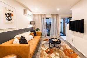A modern living room with a sofa, a coffee table, and a flat-screen TV.