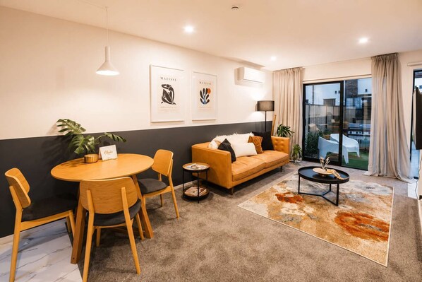 A modern living room with a round wooden table, two sofas, and a coffee table.