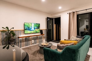 A modern living room with a flat-screen TV, a sofa, a coffee table, and a plant. - Central Stay – Sleeps 5 | Walk to Te Pae & Casino (Christchurch)