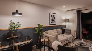A modern living room with a sofa, coffee table, and a dining area with a glass table.