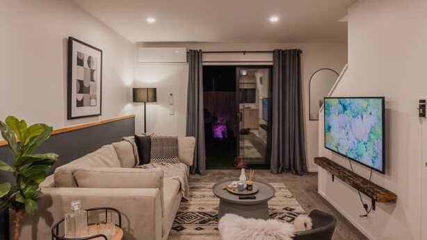 A modern living room with a sofa, coffee table, and a flat-screen TV mounted on the wall.