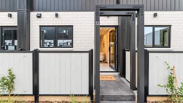 A modern building with a black metal gate, a welcome mat, and a clear view into the interior.