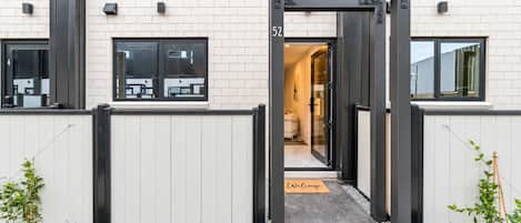 Un edificio moderno con una reja de metal negro, un felpudo y una vista despejada del interior.