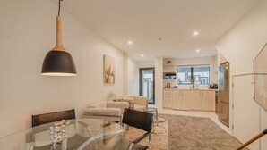 Una cocina moderna con ventana, un comedor con mesa de vidrio y una sala de estar con sofá.