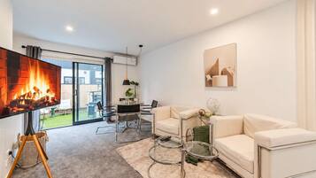 A modern living room with a flat-screen TV, a sofa, a coffee table, and a fireplace.